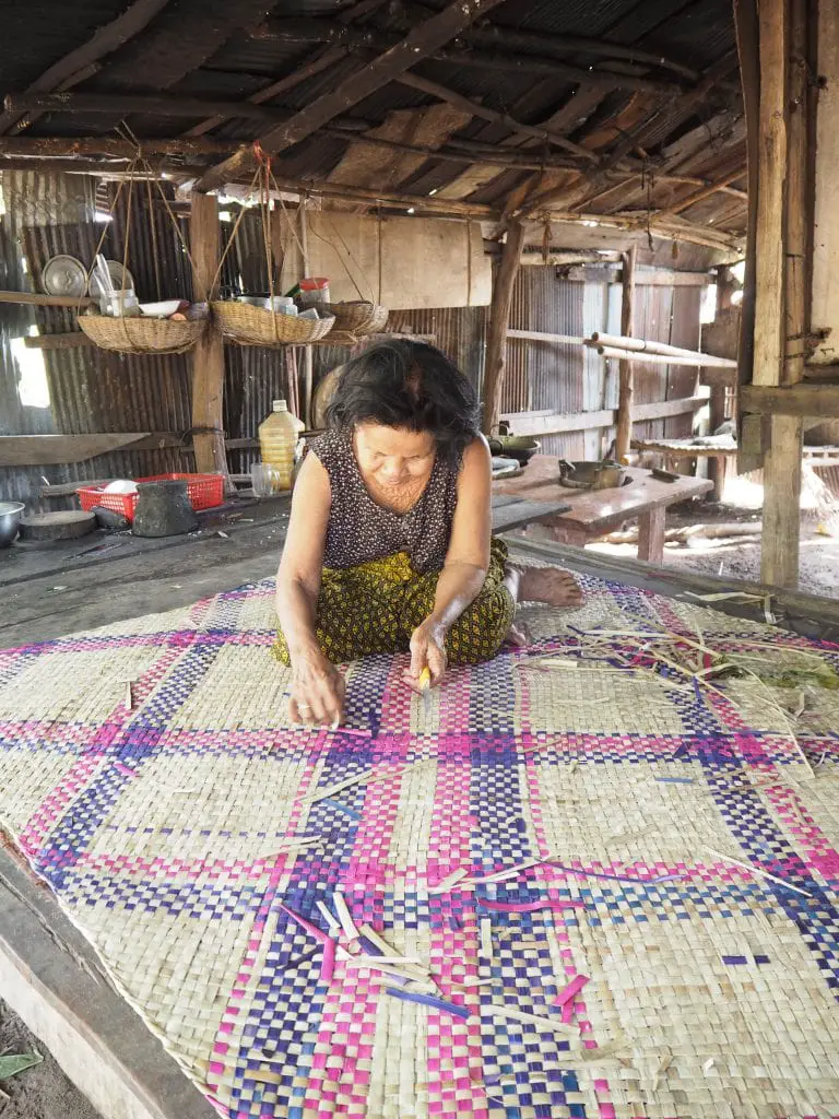 A women who was helped by the Shinta Mani Foundation making a rattan mat